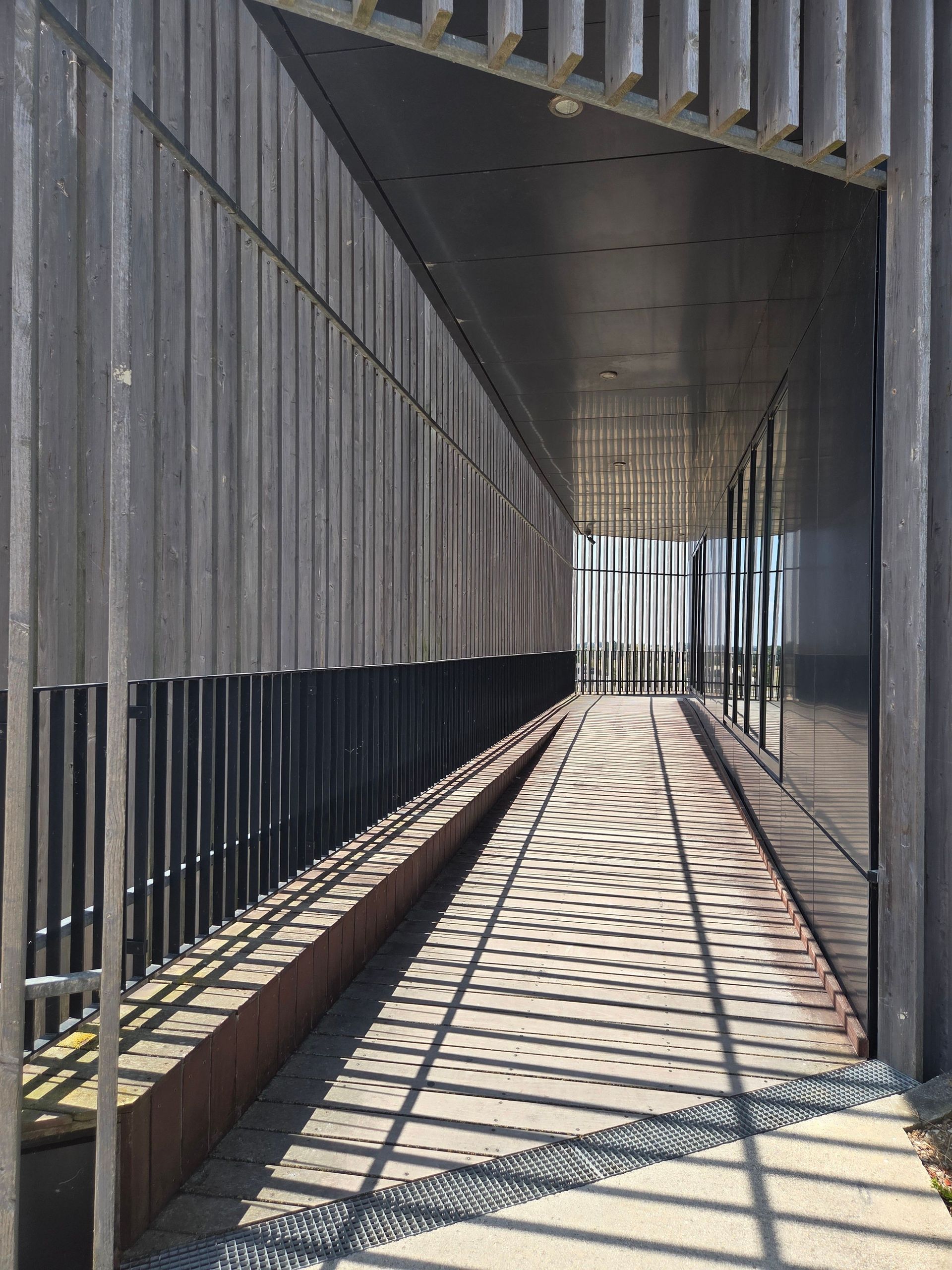 A modern architectural walkway featuring dynamic shadows and lines, creating a geometric pattern.